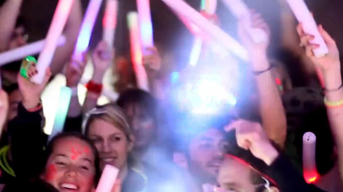 Hundreds of clubbers with hands in the air waving lightsticks and lightbands
